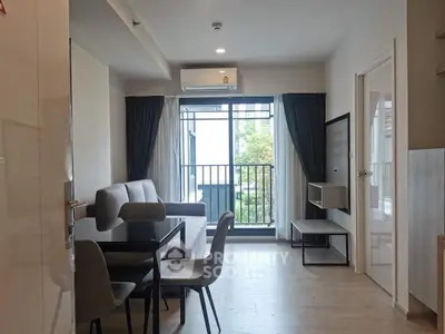 Modern living room with sleek furniture and large window offering natural light.