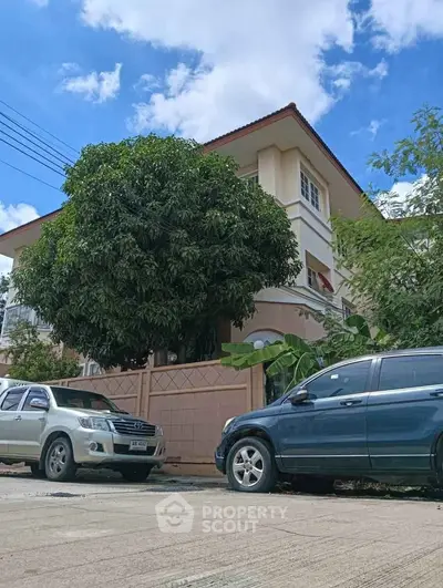 Charming suburban house with lush greenery and parked cars, perfect for family living.