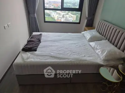 Modern bedroom with large window offering city view, featuring a stylish bed and elegant side tables.