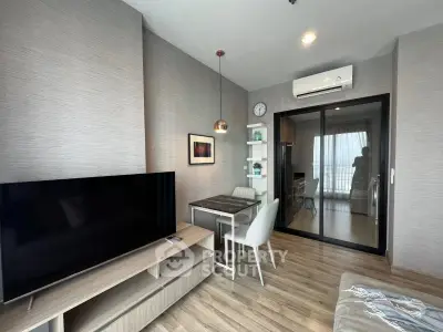 Modern living room with sleek furniture and large TV, featuring stylish decor and natural light.