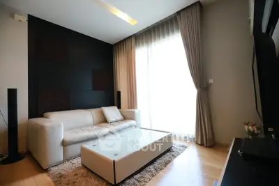 Modern living room with sleek design, featuring a white sofa, glass coffee table, and floor-to-ceiling window.