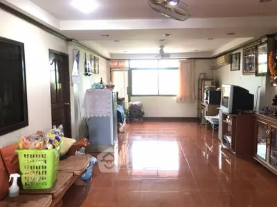 Spacious living room with tiled floor and natural light, featuring a TV and ceiling fan.