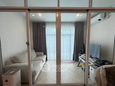 Modern living room with glass sliding doors, cozy sofa, and entertainment setup.