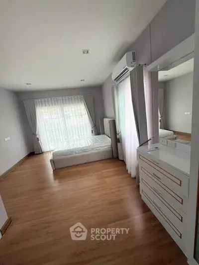 Spacious bedroom with large windows and modern furnishings in a stylish home.