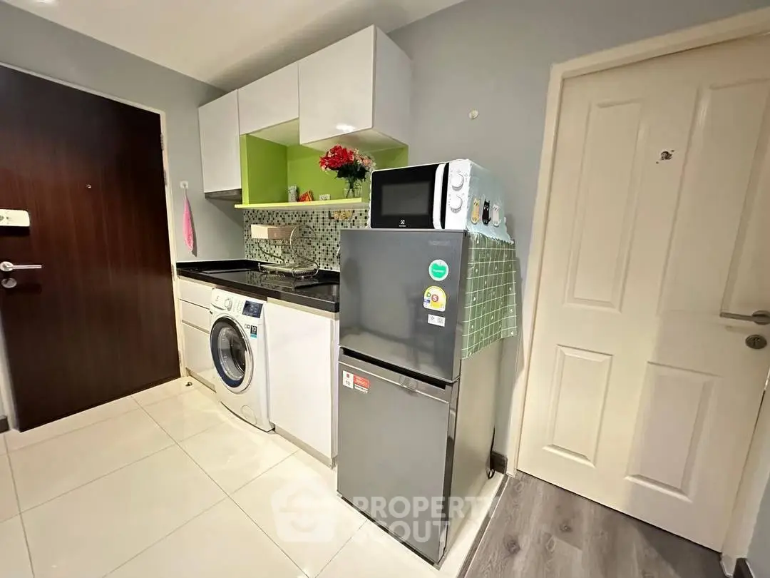 Compact kitchen with washing machine and fridge in modern apartment