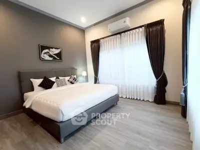 Modern bedroom with stylish decor and large window, featuring a comfortable bed and elegant curtains.