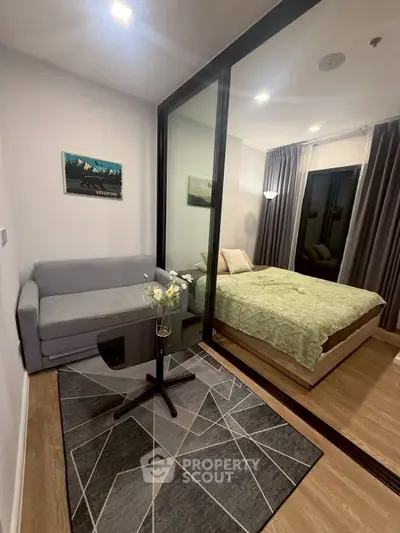 Modern bedroom with glass partition and cozy sitting area, featuring stylish decor and ambient lighting.