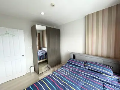 Modern bedroom with striped bedding and mirrored wardrobe in a bright, minimalist design.