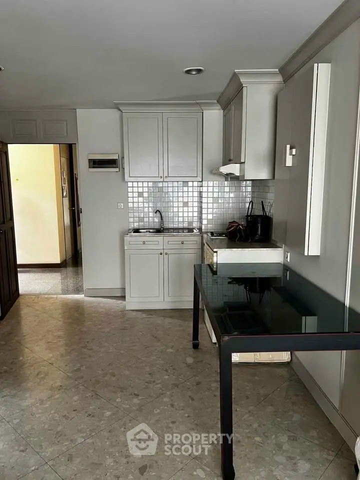 Modern kitchen with sleek cabinetry and tiled backsplash in a cozy apartment setting.