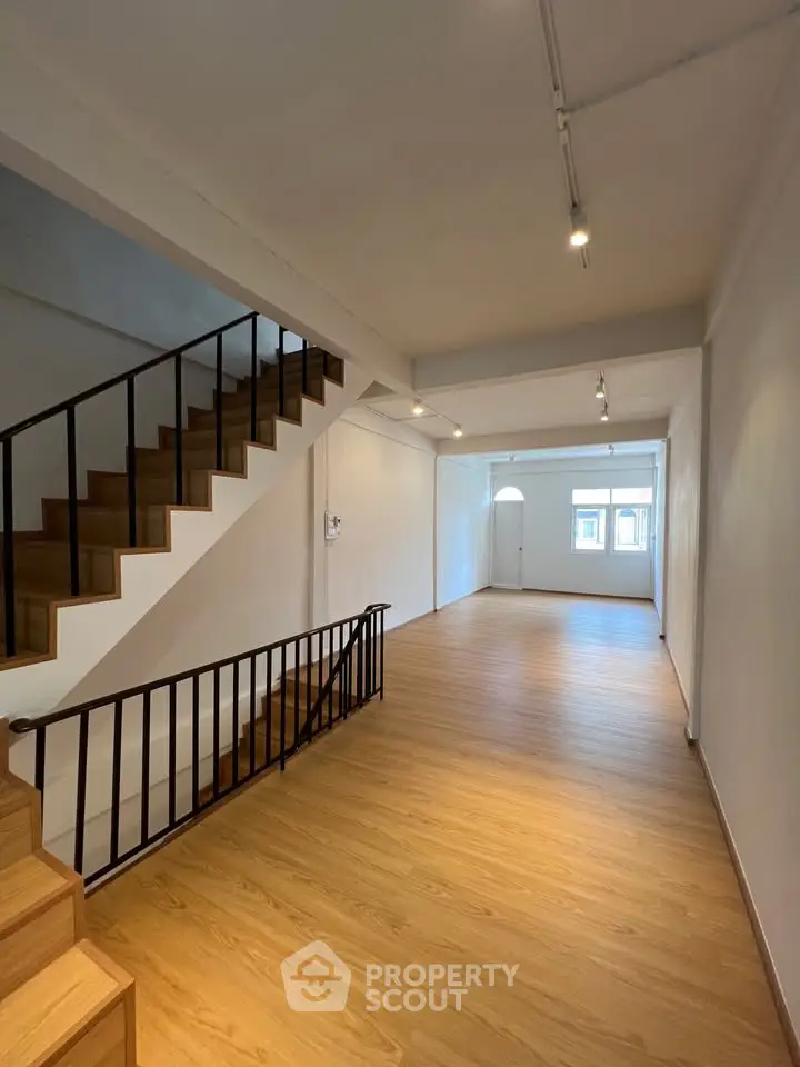 Spacious modern interior with wooden flooring and staircase, ideal for stylish living.