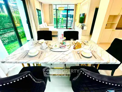 Luxurious dining area with elegant marble table and plush chairs in a modern open-plan living space.