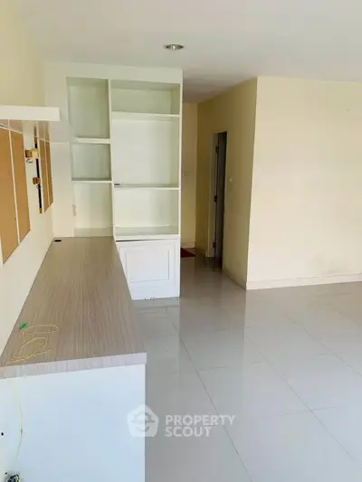 Spacious modern living room with sleek built-in shelving and glossy tiled flooring.