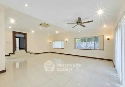 Spacious living room with modern ceiling fan and large windows, perfect for natural light.