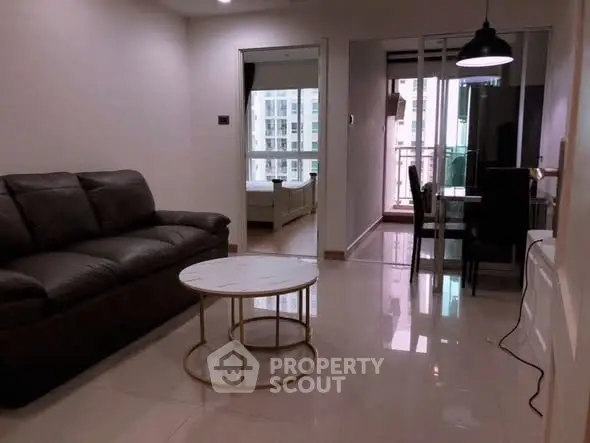 Modern living room with sleek furniture and balcony view in urban apartment.