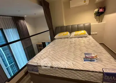 Modern bedroom with large window and stylish decor in a high-rise apartment.