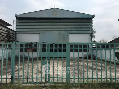 Industrial warehouse exterior with gated entrance and metal facade