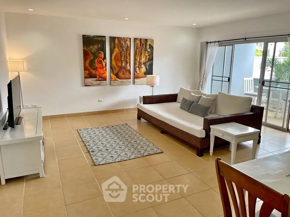 Spacious living room with modern decor and large windows leading to a balcony.
