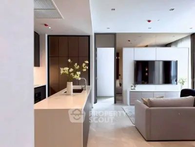 Modern open-plan living room with sleek kitchen and large TV, perfect for entertaining.