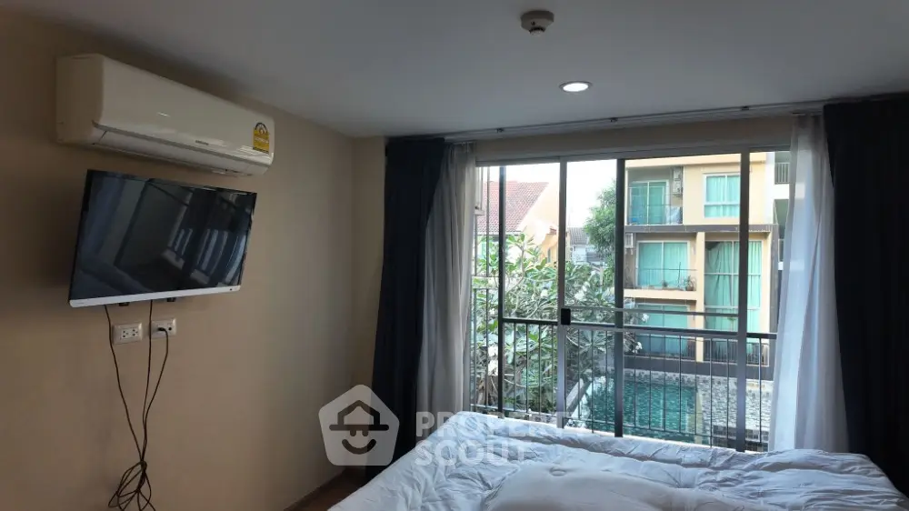 Modern bedroom with balcony view and wall-mounted TV in stylish apartment