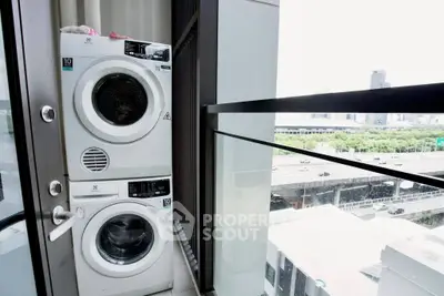 Modern apartment balcony with stacked washer and dryer overlooking cityscape.