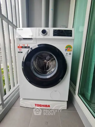 Modern Toshiba washing machine on a balcony with city view, perfect for urban living convenience.