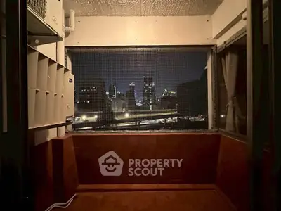 Cozy balcony with city skyline view at night, perfect for relaxation.