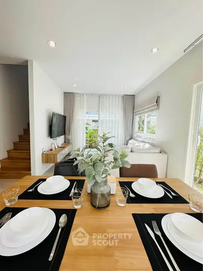 Modern open-plan living room with dining area, stylish decor, and natural light.