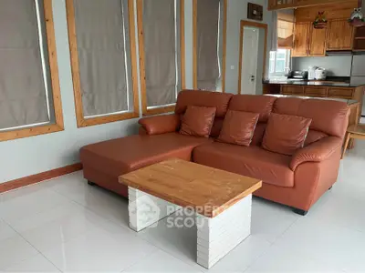 Spacious living room with modern leather sofa and wooden accents, perfect for relaxation and entertaining.