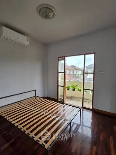 Spacious bedroom with balcony access and wooden flooring in modern home.