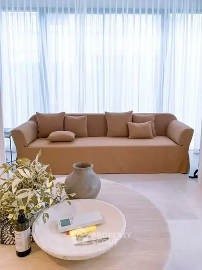 Elegant living room with beige sofa and sheer curtains, perfect for modern interiors.