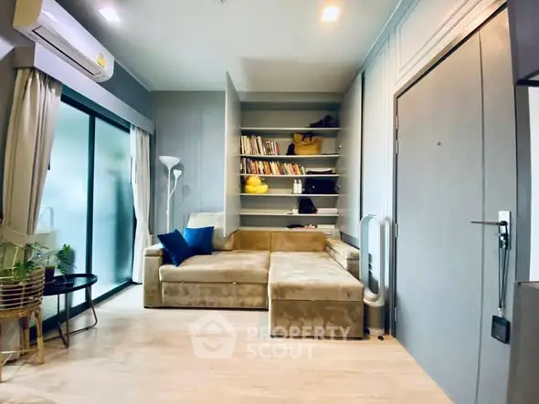 Modern living room with cozy beige sofa, built-in shelves, and sliding glass doors to balcony.