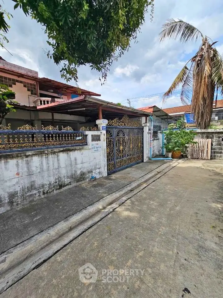 Charming residential property with ornate gate and lush greenery in a serene neighborhood.