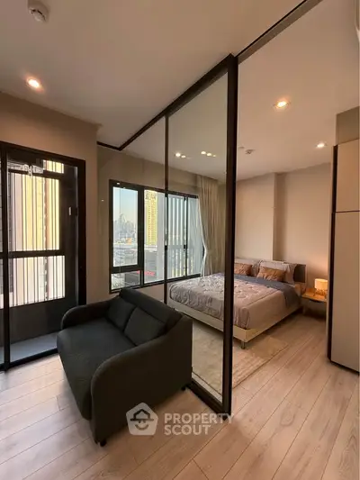Modern bedroom with glass partition and city view, featuring cozy seating area and elegant decor.