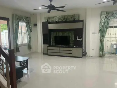 Spacious living room with modern entertainment center and elegant curtains, perfect for family gatherings.