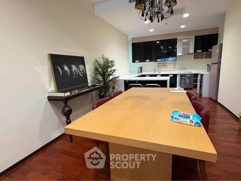 Modern dining area with wooden table and sleek kitchen in open layout.