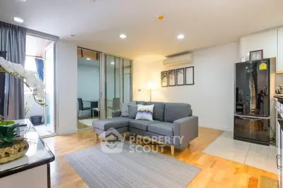 Modern living room with stylish decor and open layout, featuring a cozy gray sofa and sleek appliances.