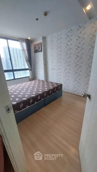 Spacious bedroom with large window and modern decor in high-rise apartment