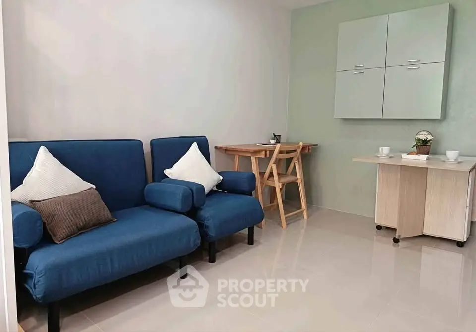 Cozy living room with blue sofa and compact dining area, perfect for modern urban living.