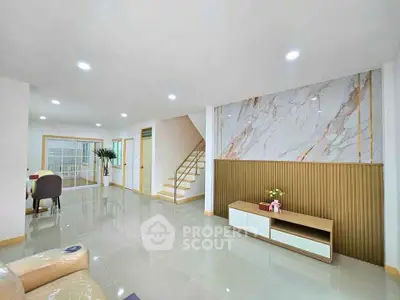 Spacious modern living room with elegant marble accent wall and sleek furniture.