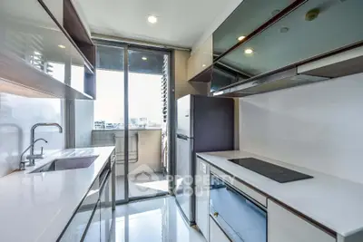 Modern kitchen with sleek design and balcony view in a high-rise apartment.