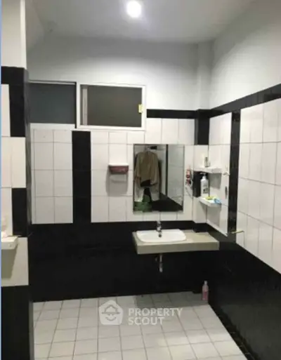 Modern bathroom with sleek black and white tiles and a wall-mounted sink.