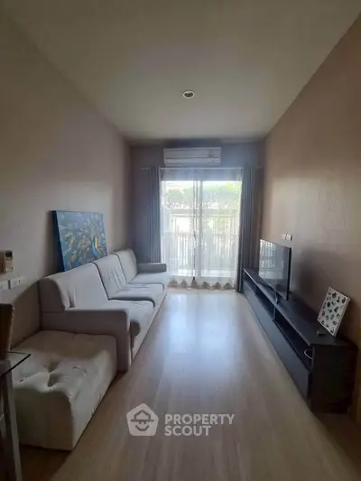 Modern living room with sleek furniture and large window offering natural light.