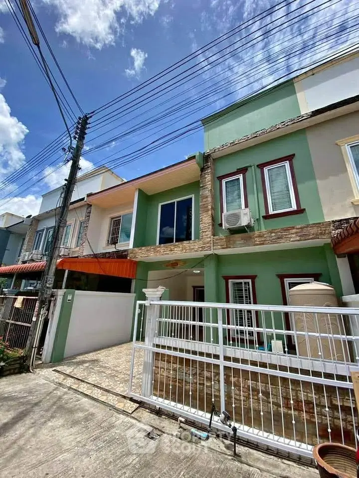 Charming townhouse with vibrant facade and gated entrance in a sunny neighborhood.
