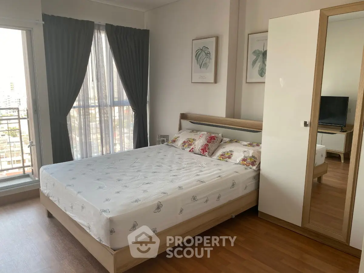 Spacious bedroom with modern decor and large windows offering natural light.