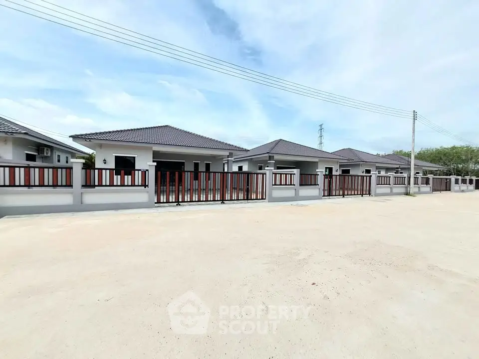 Modern single-story homes with fenced yards under a clear blue sky.