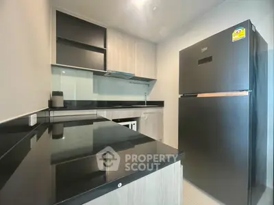 Modern kitchen with sleek black countertops and stainless steel appliances in a stylish apartment.