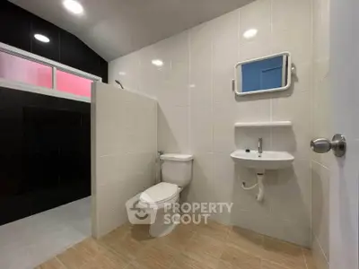 Modern bathroom with sleek design and tiled walls, featuring a toilet and sink.