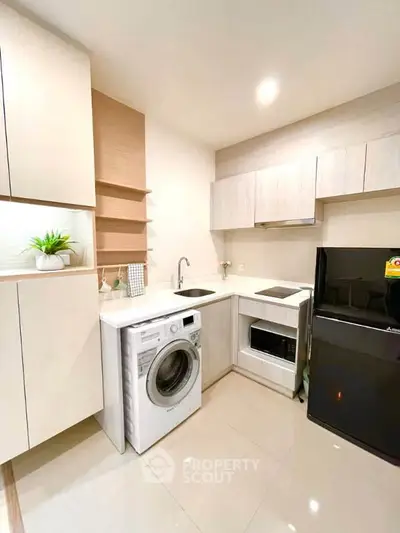 Modern kitchen with sleek appliances and stylish cabinetry, featuring a washing machine and refrigerator.