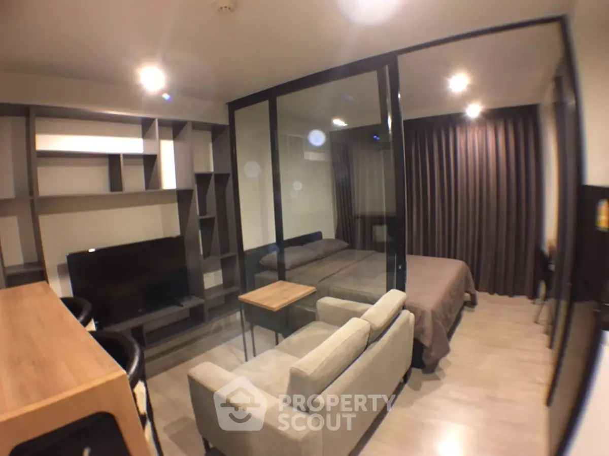 Modern studio apartment with glass partition, cozy living area, and stylish shelving.