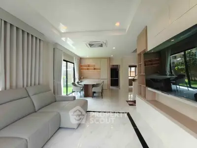 Luxurious modern living room with elegant furnishings and large windows offering garden views.